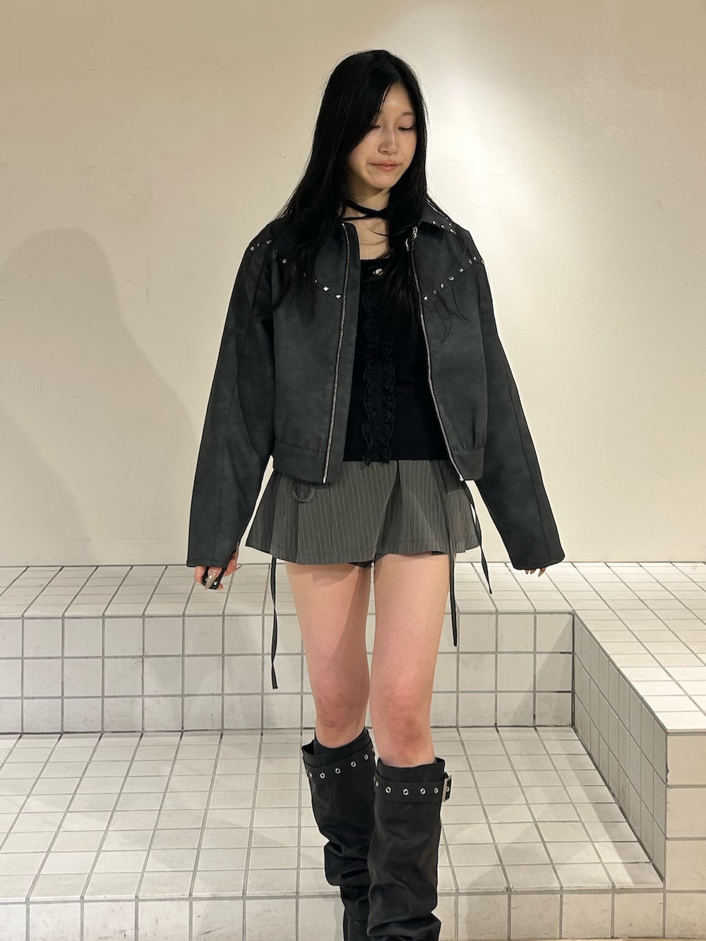 ブラック系のブーツ、グレー系のスカート、ブラック系のブルゾンを着用したレディースの冬コーディネートの4枚目の写真