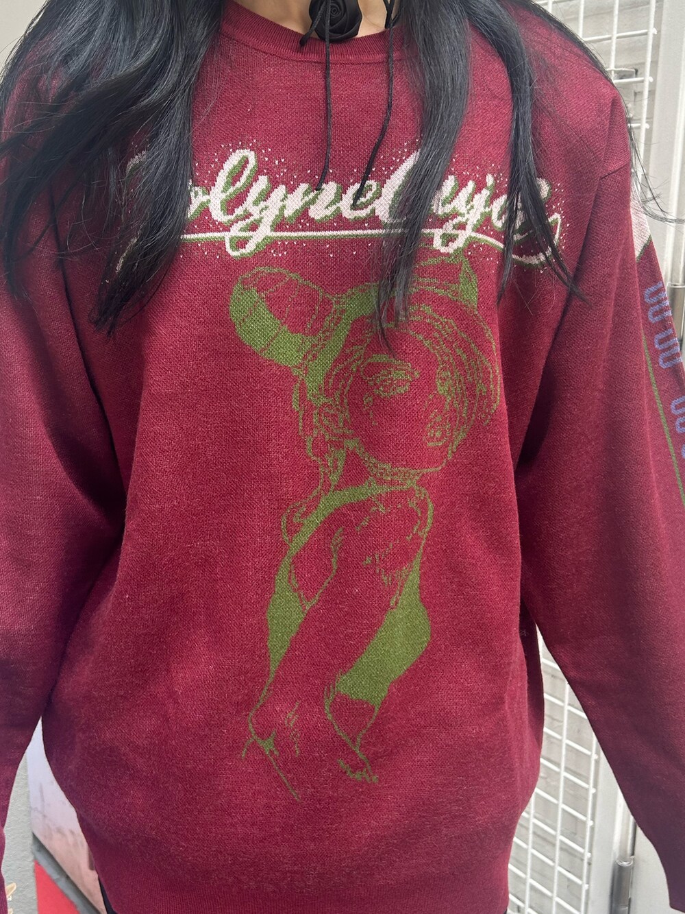 レッド系のニット/セーター、ブラック系のスカート、ブラック系のチョーカーを着用したレディースの秋コーディネートの6枚目の写真