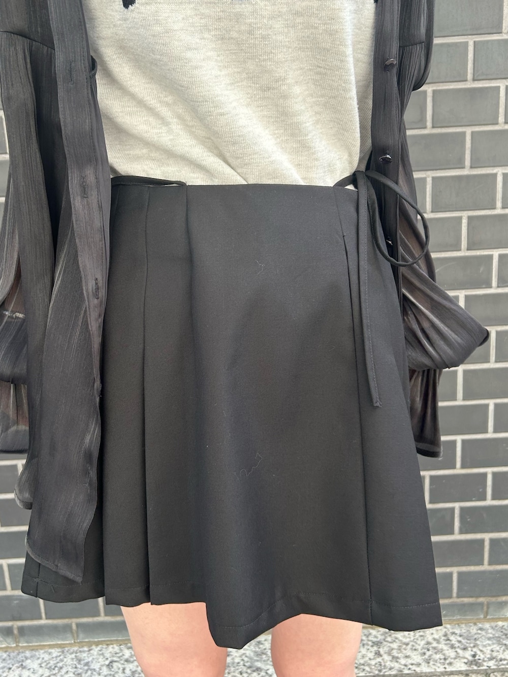 ブラック系のシャツ/ブラウス、ホワイト系のニット/セーター、ブラック系のスカートを着用したレディースの春コーディネートの7枚目の写真