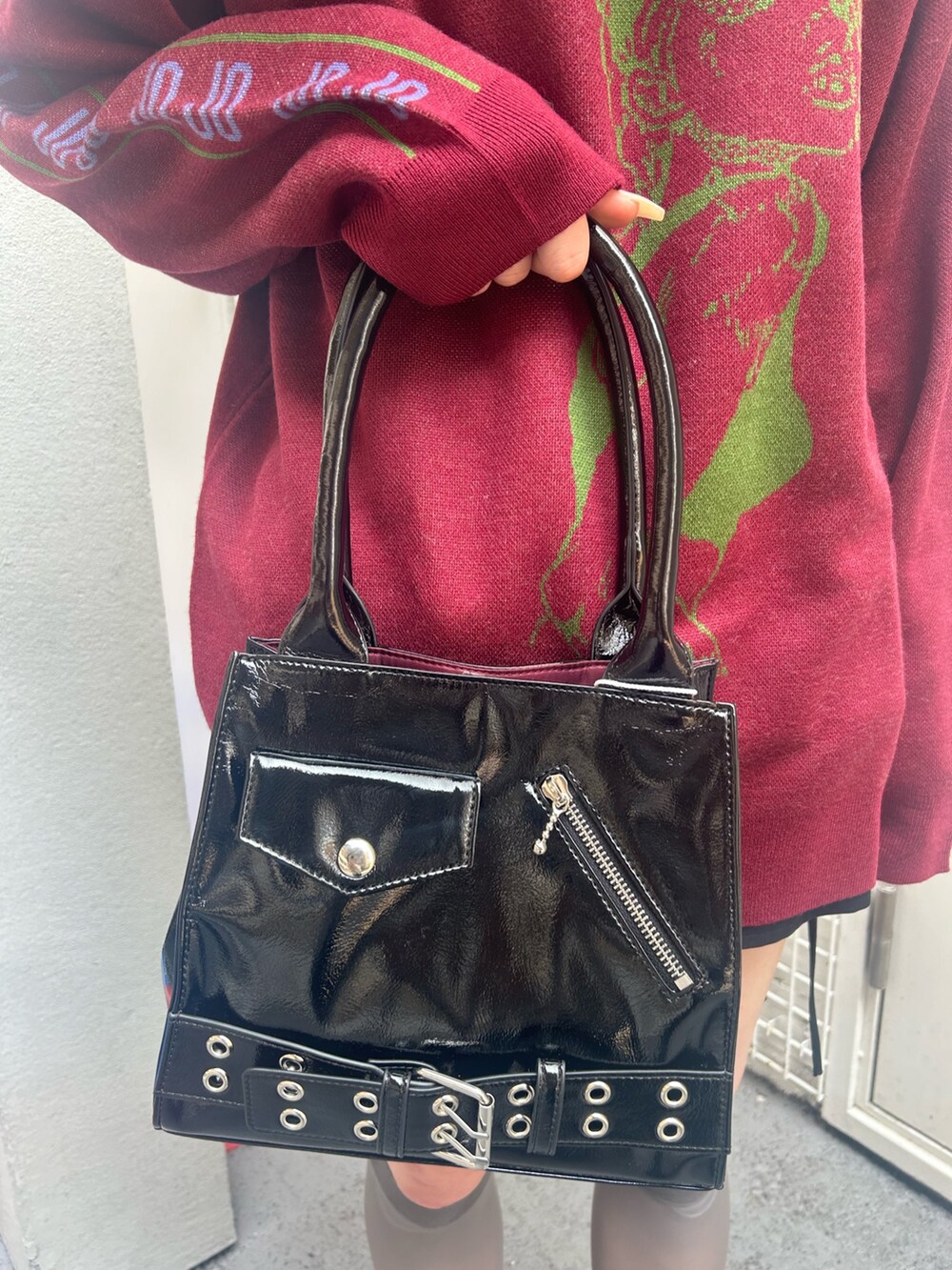 レッド系のニット/セーター、ブラック系のスカート、ブラック系のチョーカーを着用したレディースの秋コーディネートの9枚目の写真