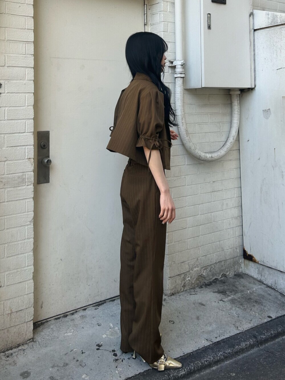 ゴールド系のパンプス、ブラック系のニット/セーター、ブラウン系のその他パンツを着用したレディースの冬コーディネートの2枚目の写真