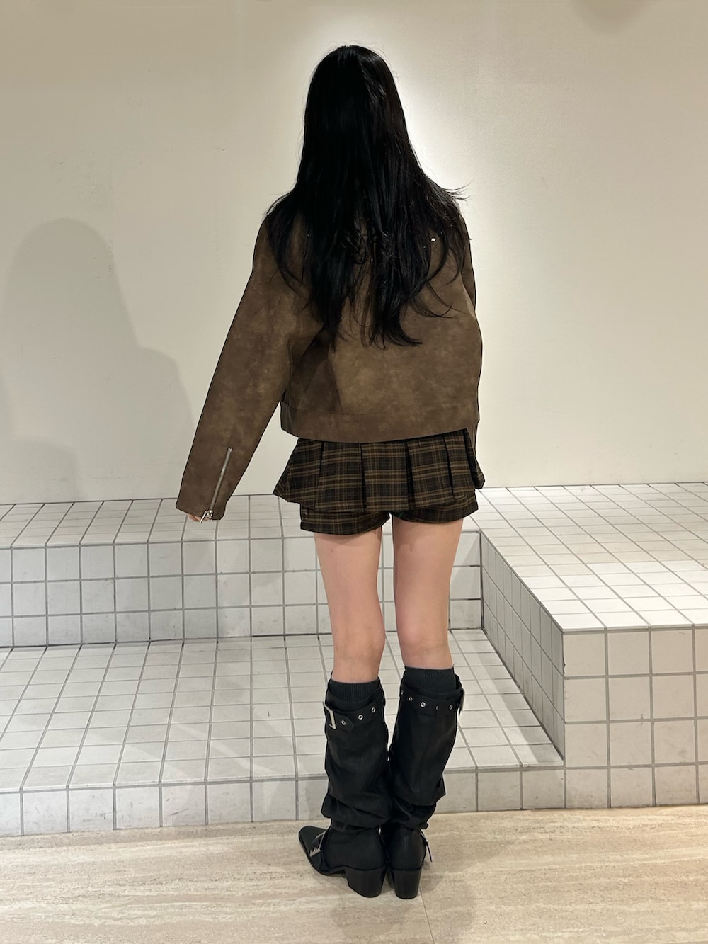 ブラック系のブーツ、ブラウン系のスカート、ブラウン系のブルゾンを着用したレディースの冬コーディネートの3枚目の写真