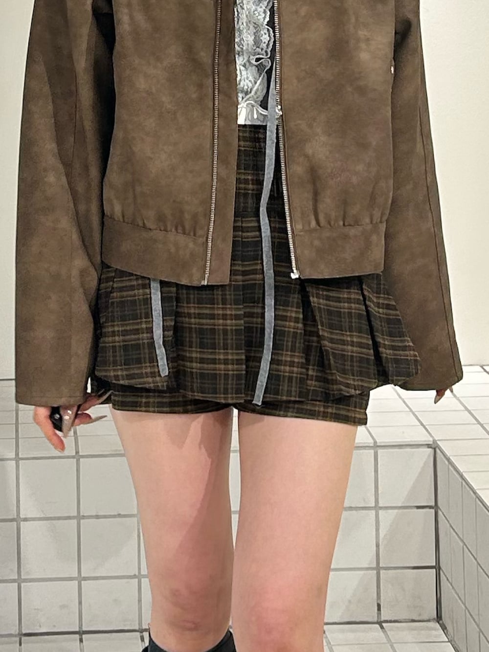 ブラック系のブーツ、ブラウン系のスカート、ブラウン系のブルゾンを着用したレディースの冬コーディネートの7枚目の写真