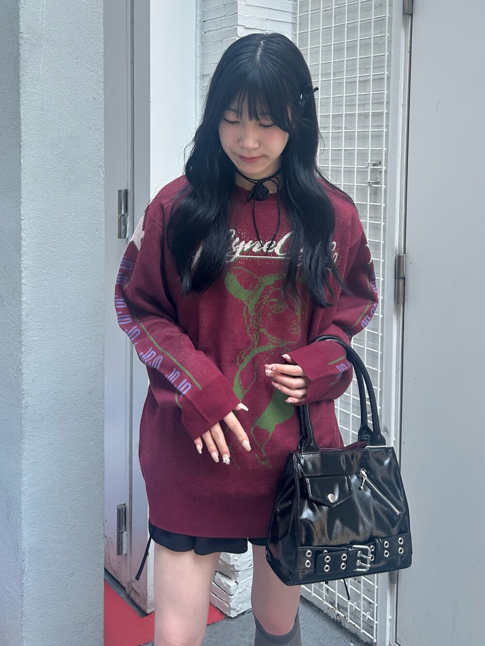 レッド系のニット/セーター、ブラック系のスカート、ブラック系のチョーカーを着用したレディースの秋コーディネートの4枚目の写真