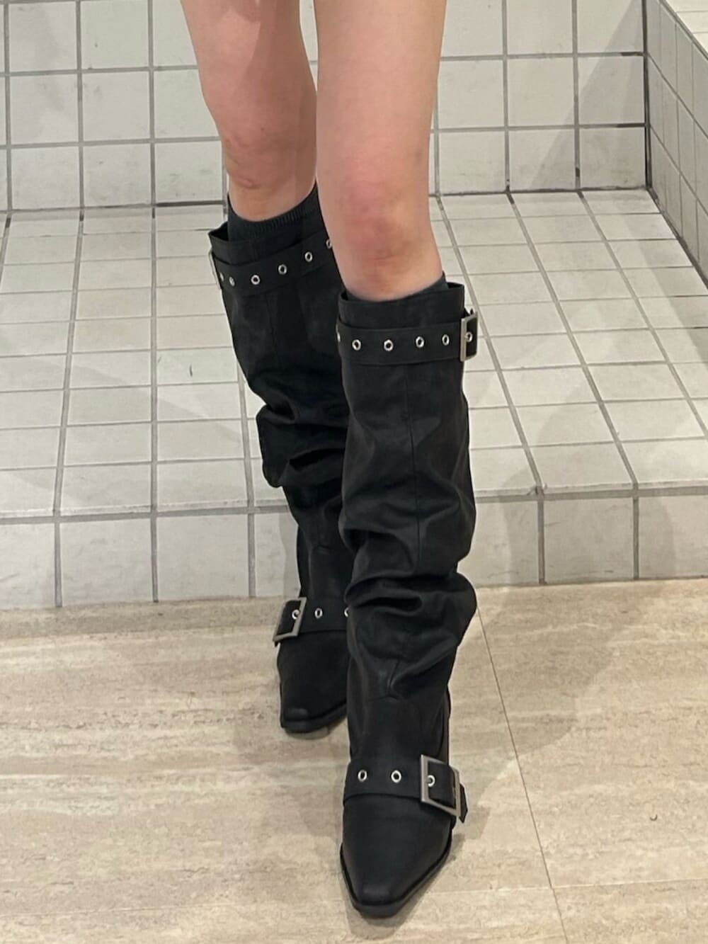 ブラウン系のスカート、グレー系のスウェット、ブラック系のブーツを着用したレディースの冬コーディネートの6枚目の写真