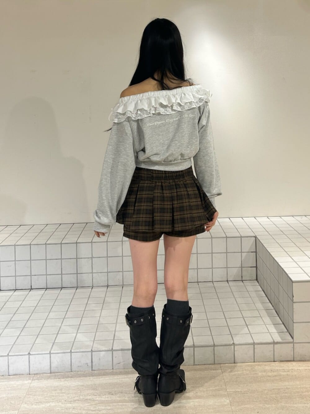 ブラウン系のスカート、グレー系のスウェット、ブラック系のブーツを着用したレディースの冬コーディネートの3枚目の写真