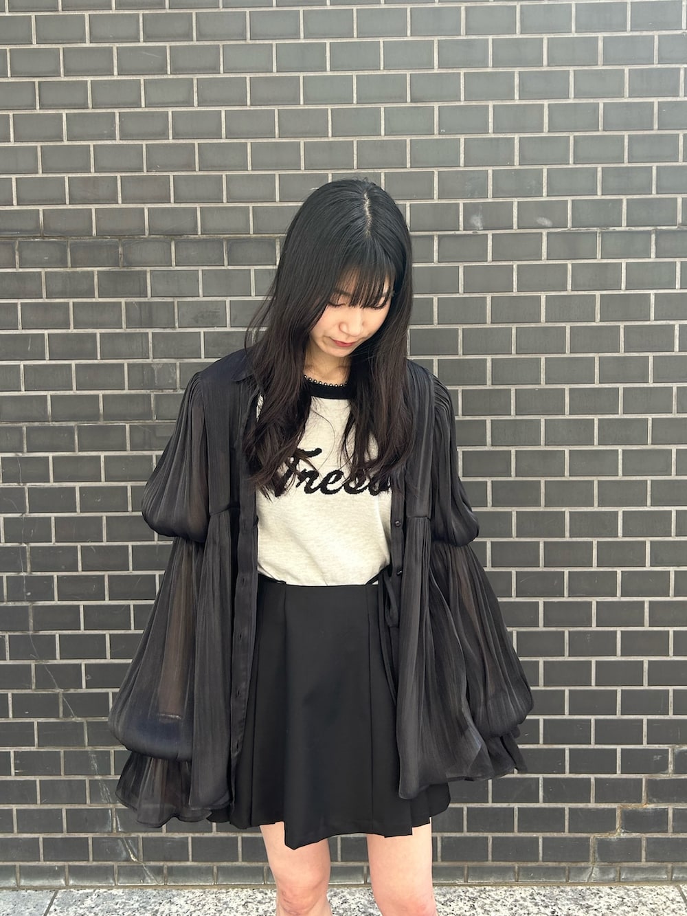 ブラック系のシャツ/ブラウス、ホワイト系のニット/セーター、ブラック系のスカートを着用したレディースの春コーディネートの4枚目の写真