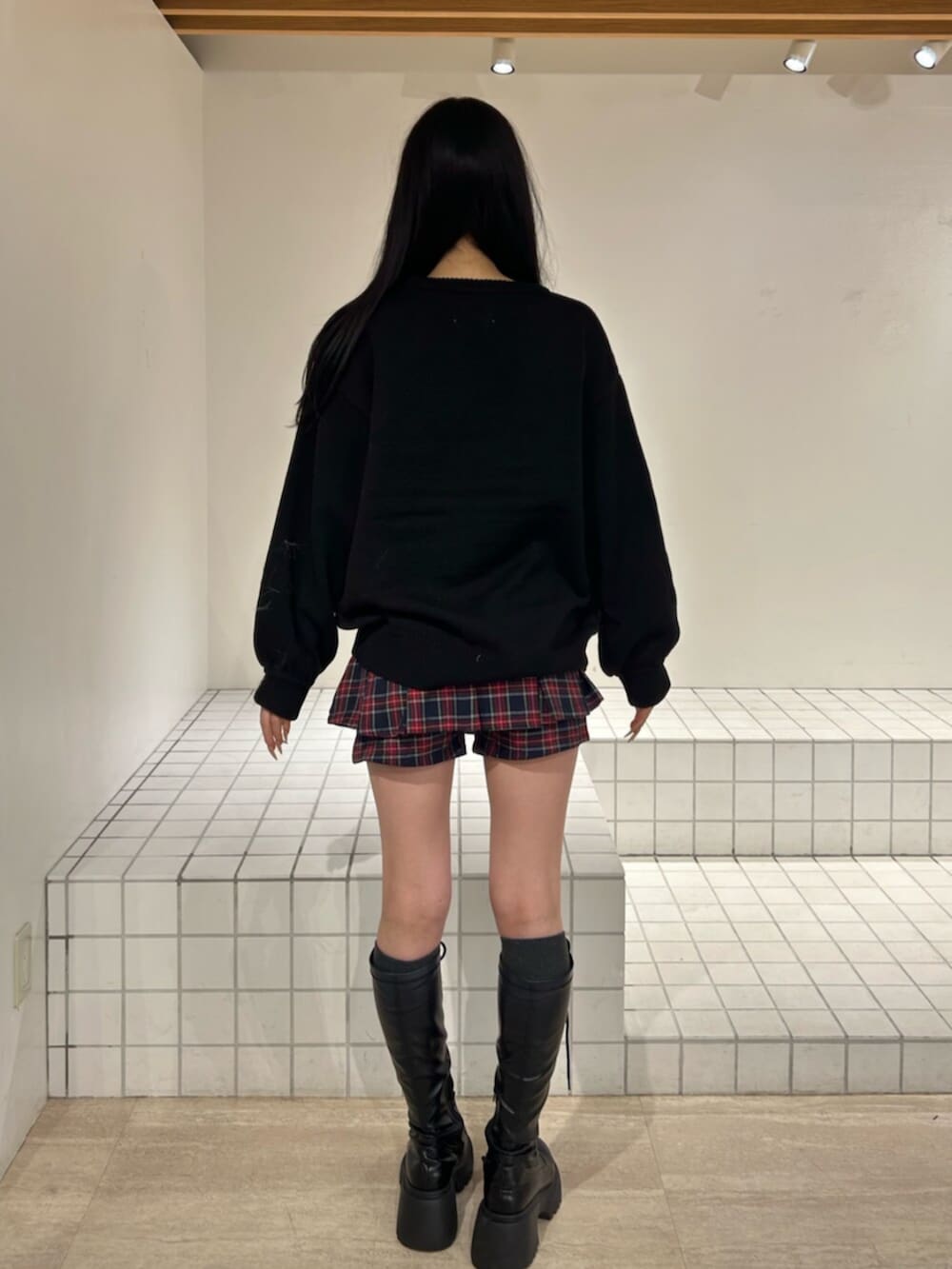 ブラック系のブーツ、ブラック系のニット/セーター、ブルー系のスカートを着用したレディースの秋コーディネートの3枚目の写真