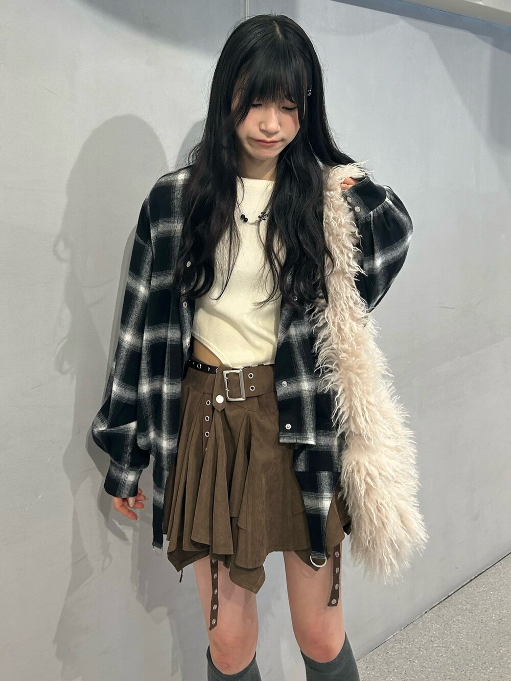 ホワイト系のショルダーバッグ、ベージュ系のブーツ、ブラウン系のスカートを着用したレディースの秋コーディネートの2枚目の写真