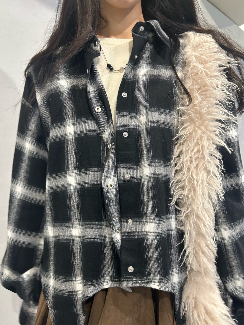 ホワイト系のショルダーバッグ、ベージュ系のブーツ、ブラウン系のスカートを着用したレディースの秋コーディネートの6枚目の写真