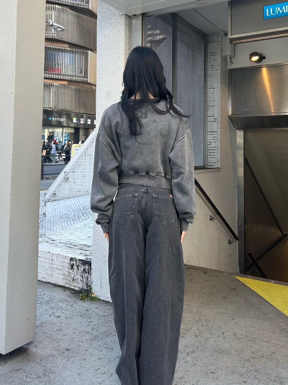 ブラック系のデニムパンツ、ブラック系のスウェット、ブラック系のパンプスを着用したレディースの冬コーディネートの3枚目の写真