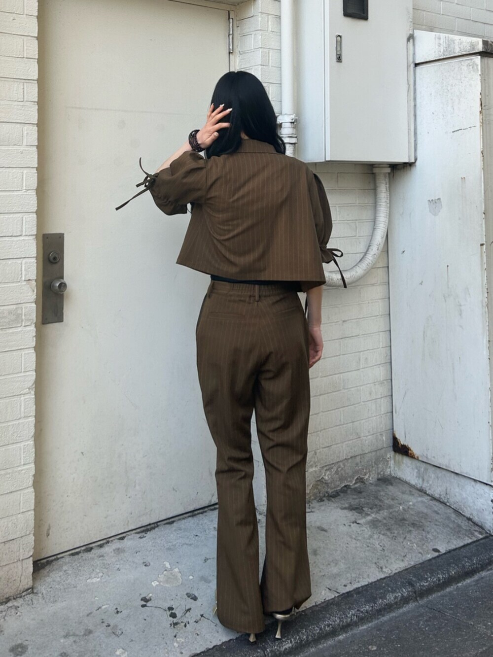 ゴールド系のパンプス、ブラック系のニット/セーター、ブラウン系のその他パンツを着用したレディースの冬コーディネートの3枚目の写真