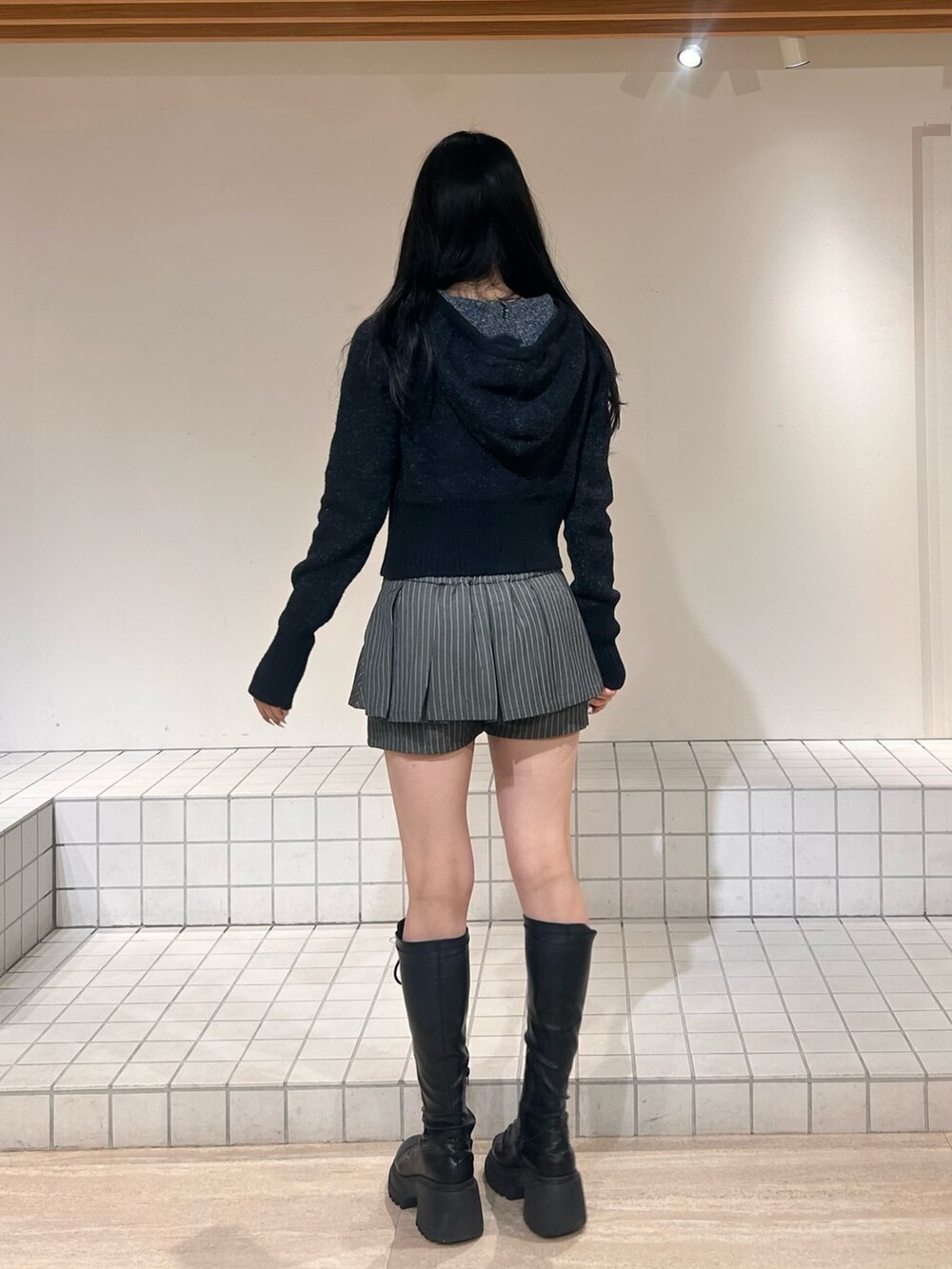 ブラック系のパーカー、グレー系のスカート、ブラック系のブーツを着用したレディースの冬コーディネートの3枚目の写真