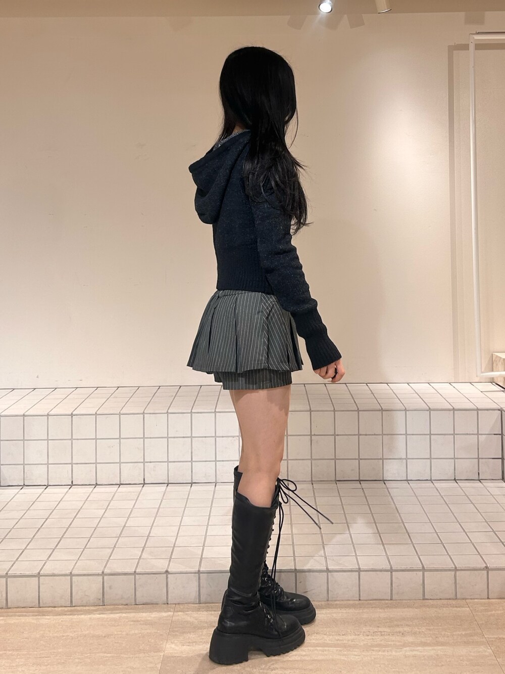 ブラック系のパーカー、グレー系のスカート、ブラック系のブーツを着用したレディースの冬コーディネートの2枚目の写真