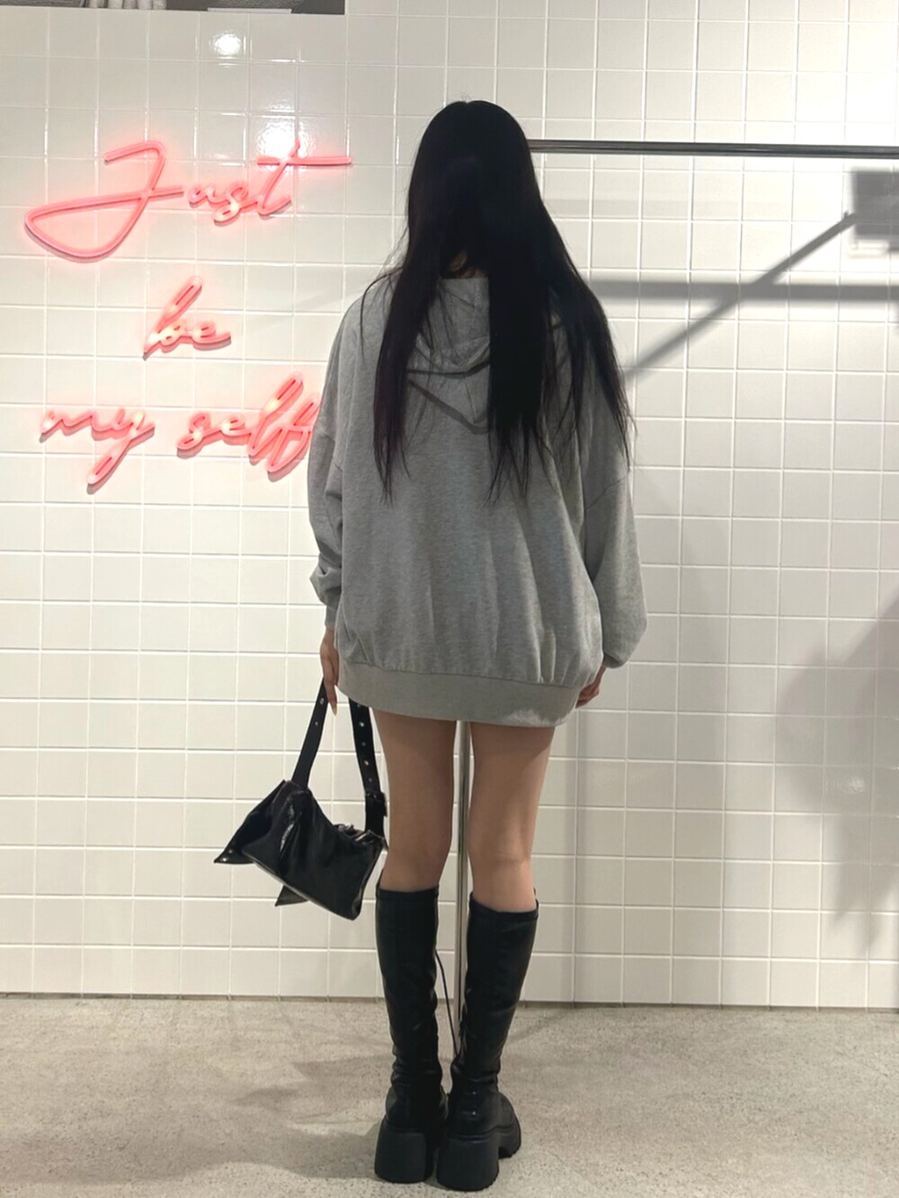 ブラック系のブーツ、グレー系のパーカー、ブラック系のスカートを着用したレディースの秋コーディネートの3枚目の写真