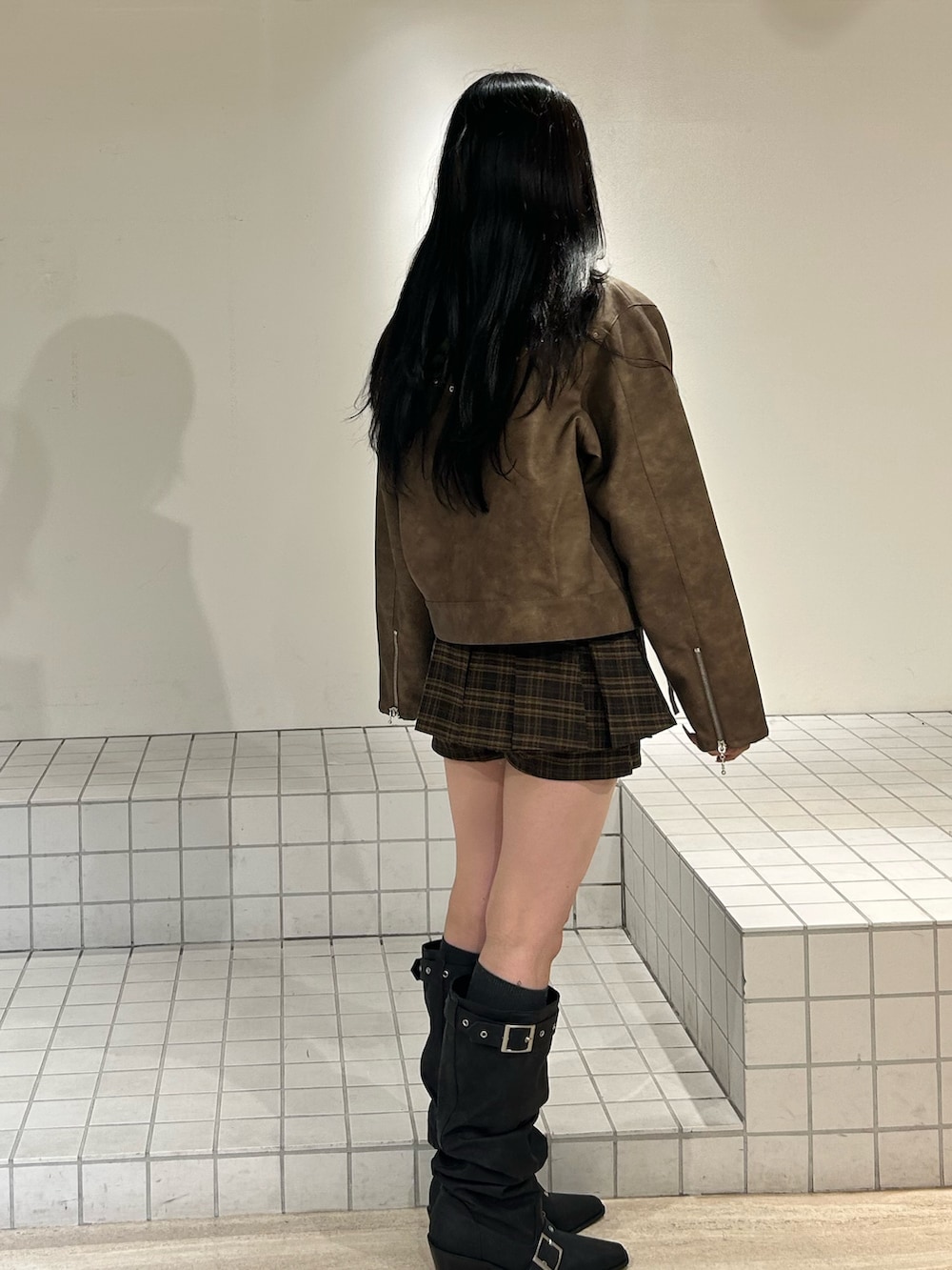 ブラック系のブーツ、ブラウン系のスカート、ブラウン系のブルゾンを着用したレディースの冬コーディネートの2枚目の写真