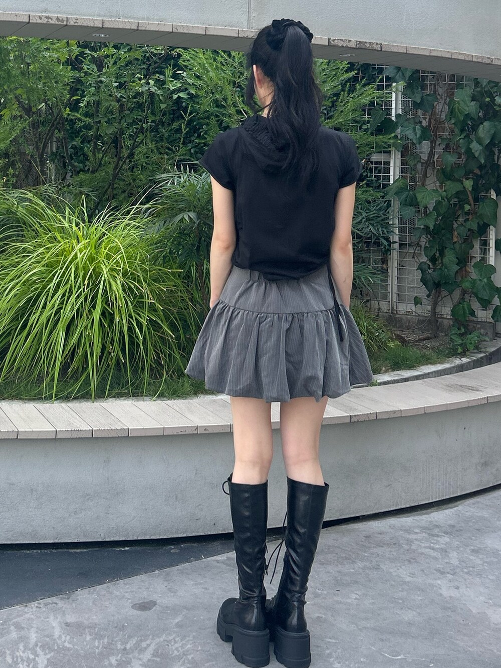グレー系のスカート、ブラック系のTシャツ/カットソー、ブラック系のブーツを着用したレディースの夏コーディネートの3枚目の写真