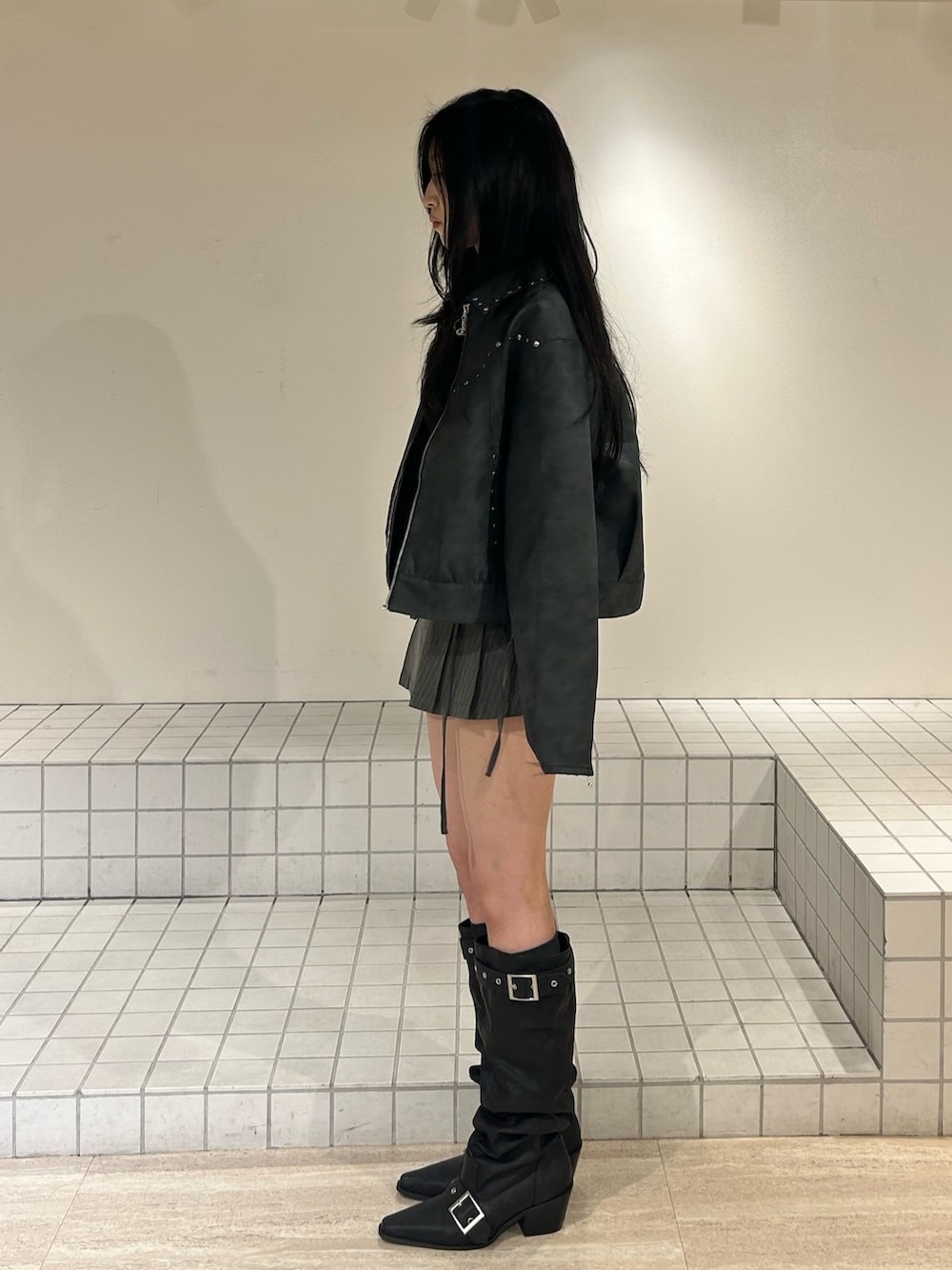 ブラック系のブーツ、グレー系のスカート、ブラック系のブルゾンを着用したレディースの冬コーディネートの2枚目の写真