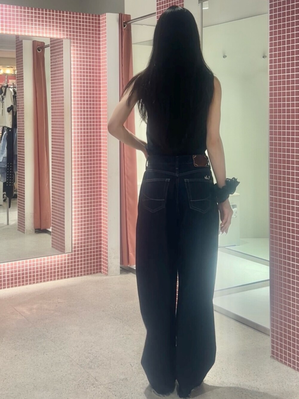 ブルー系のデニムパンツ、ブラック系のタンクトップ、ブラック系のシュシュを着用したレディースの夏コーディネートの3枚目の写真