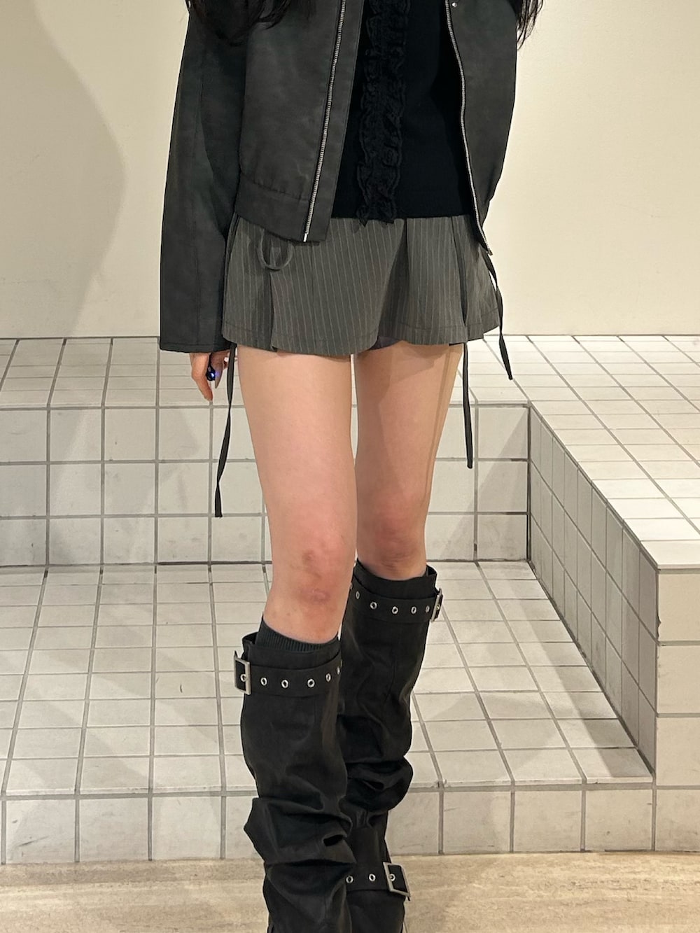 ブラック系のブーツ、グレー系のスカート、ブラック系のブルゾンを着用したレディースの冬コーディネートの7枚目の写真