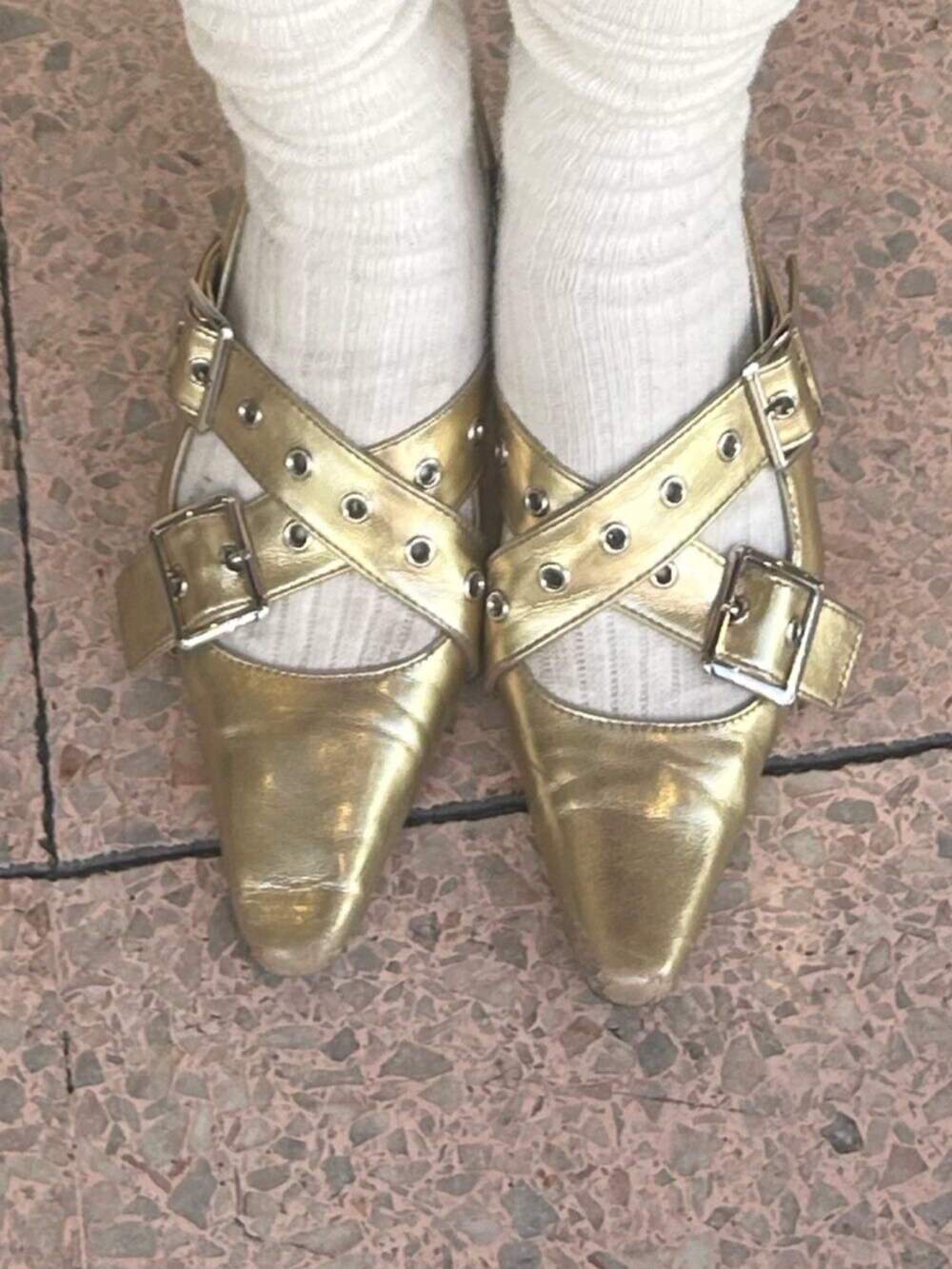 ゴールド系のパンプス、ブラック系のワンピース、ブラック系のデニムパンツを着用したレディースの冬コーディネートの8枚目の写真