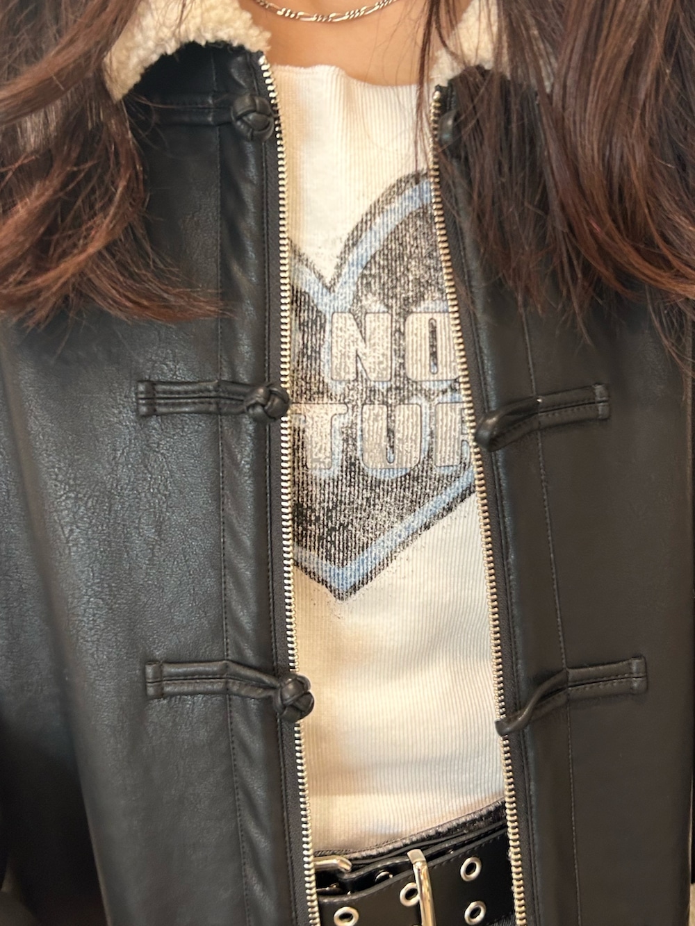 ブラック系のムートンコート、ホワイト系のTシャツ/カットソー、ブラック系のデニムパンツを着用したレディースの夏コーディネートの3枚目の写真