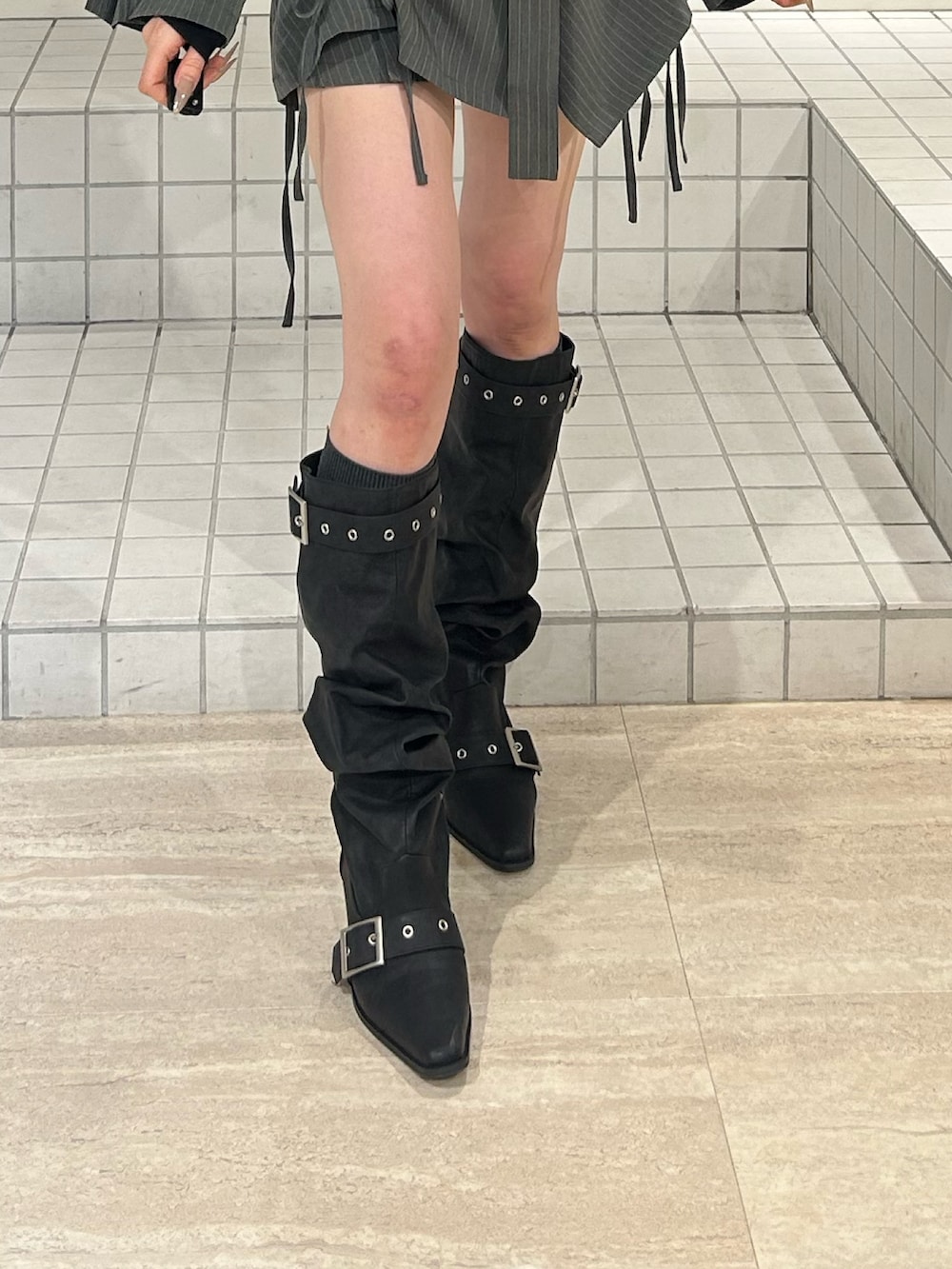 ブラック系のブーツ、グレー系のテーラードジャケット、ブラック系のニット/セーターを着用したレディースの冬コーディネートの7枚目の写真