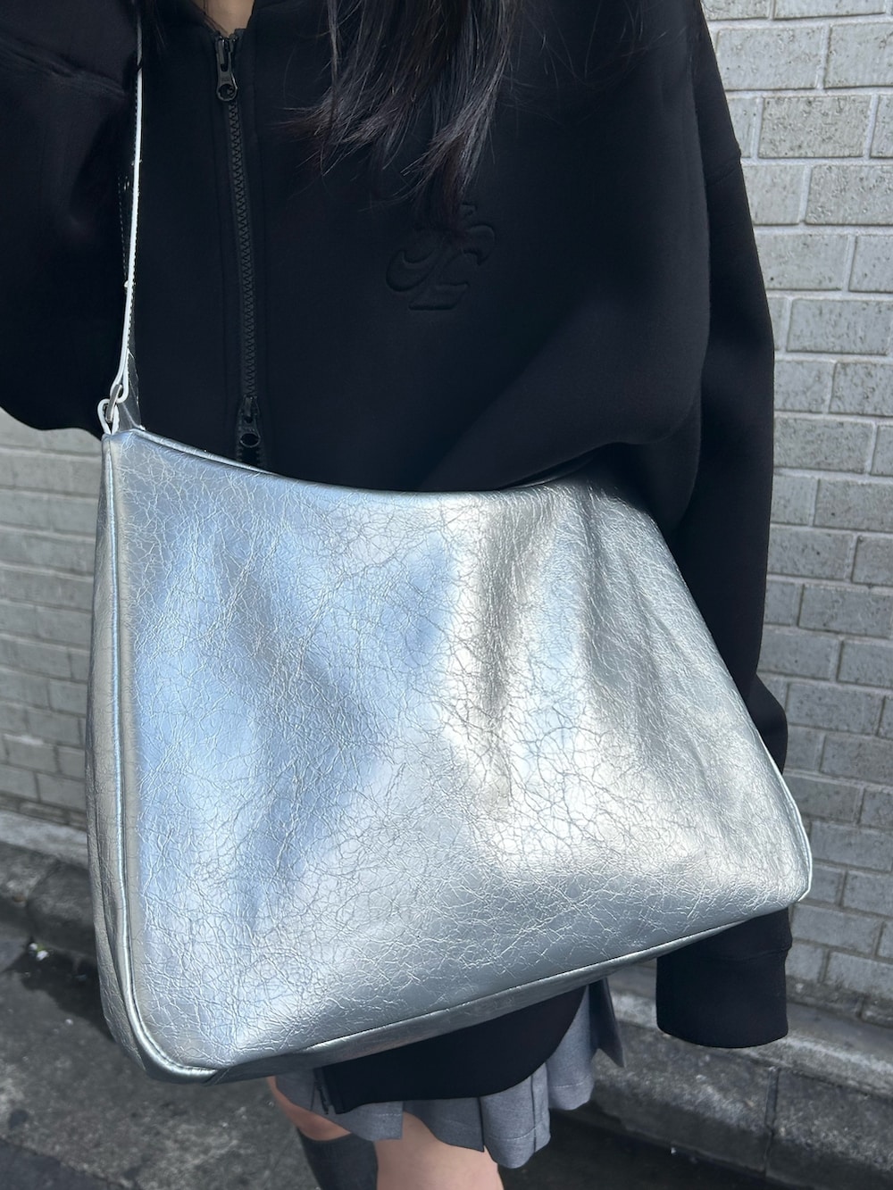 ブラック系のパーカー、グレー系のスカート、シルバー系のショルダーバッグを着用したレディースの冬コーディネートの5枚目の写真