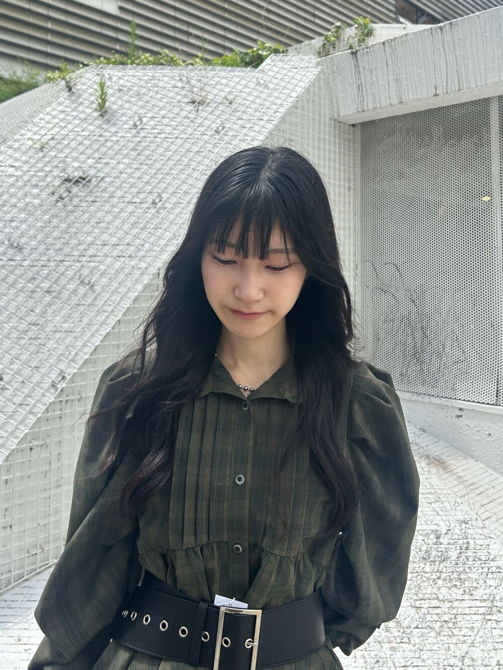 グリーン系のワンピース、ブルー系のデニムパンツ、ブラック系のベルトを着用したレディースの夏コーディネートの3枚目の写真