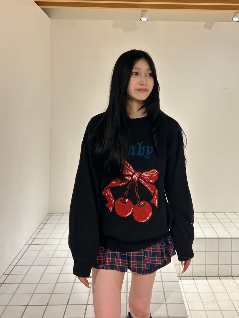 ブラック系のブーツ、ブラック系のニット/セーター、ブルー系のスカートを着用したレディースの秋コーディネートの4枚目の写真