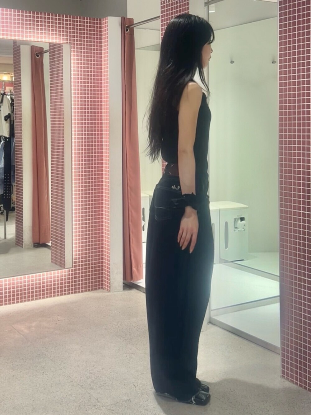 ブルー系のデニムパンツ、ブラック系のタンクトップ、ブラック系のシュシュを着用したレディースの夏コーディネートの2枚目の写真