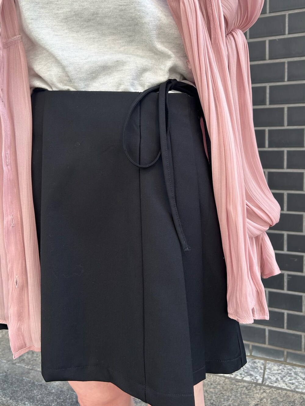 ピンク系のシャツ/ブラウス、ホワイト系のニット/セーター、ブラック系のスカートを着用したレディースの春コーディネートの6枚目の写真