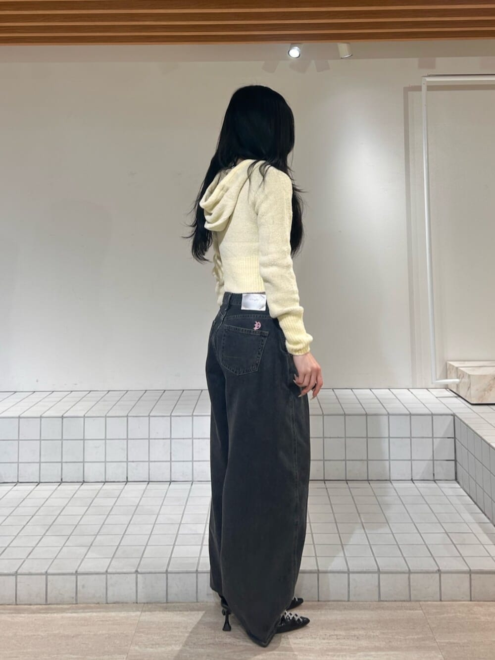 ブラック系のパンプス、ブルー系のデニムパンツ、イエロー系のパーカーを着用したレディースの冬コーディネートの2枚目の写真