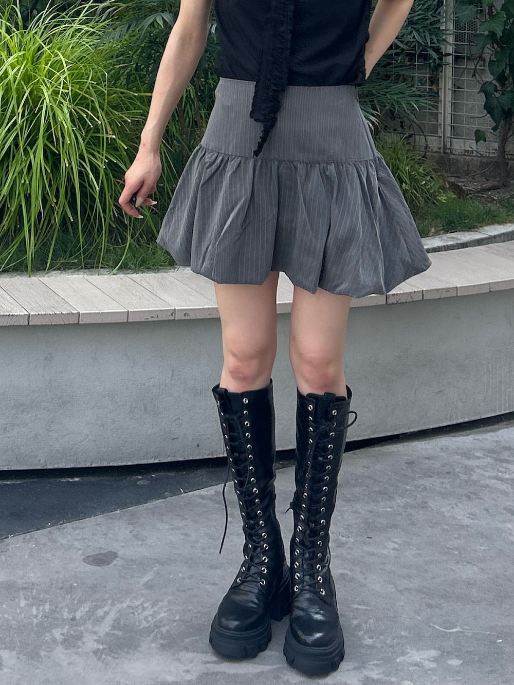 グレー系のスカート、ブラック系のTシャツ/カットソー、ブラック系のブーツを着用したレディースの夏コーディネートの6枚目の写真