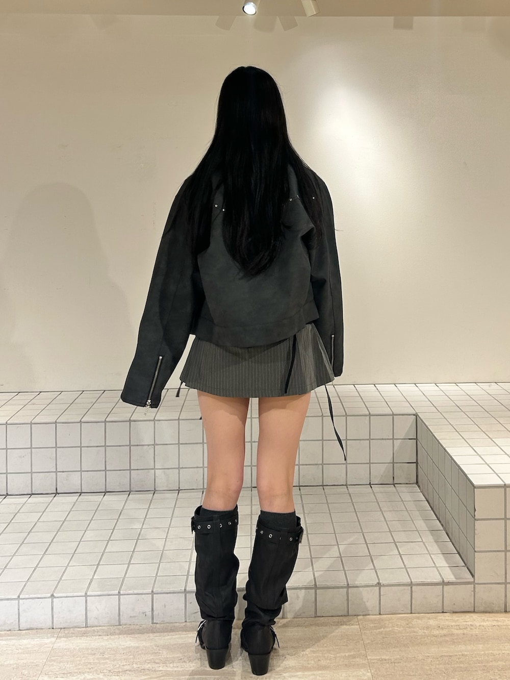 ブラック系のブーツ、グレー系のスカート、ブラック系のブルゾンを着用したレディースの冬コーディネートの3枚目の写真