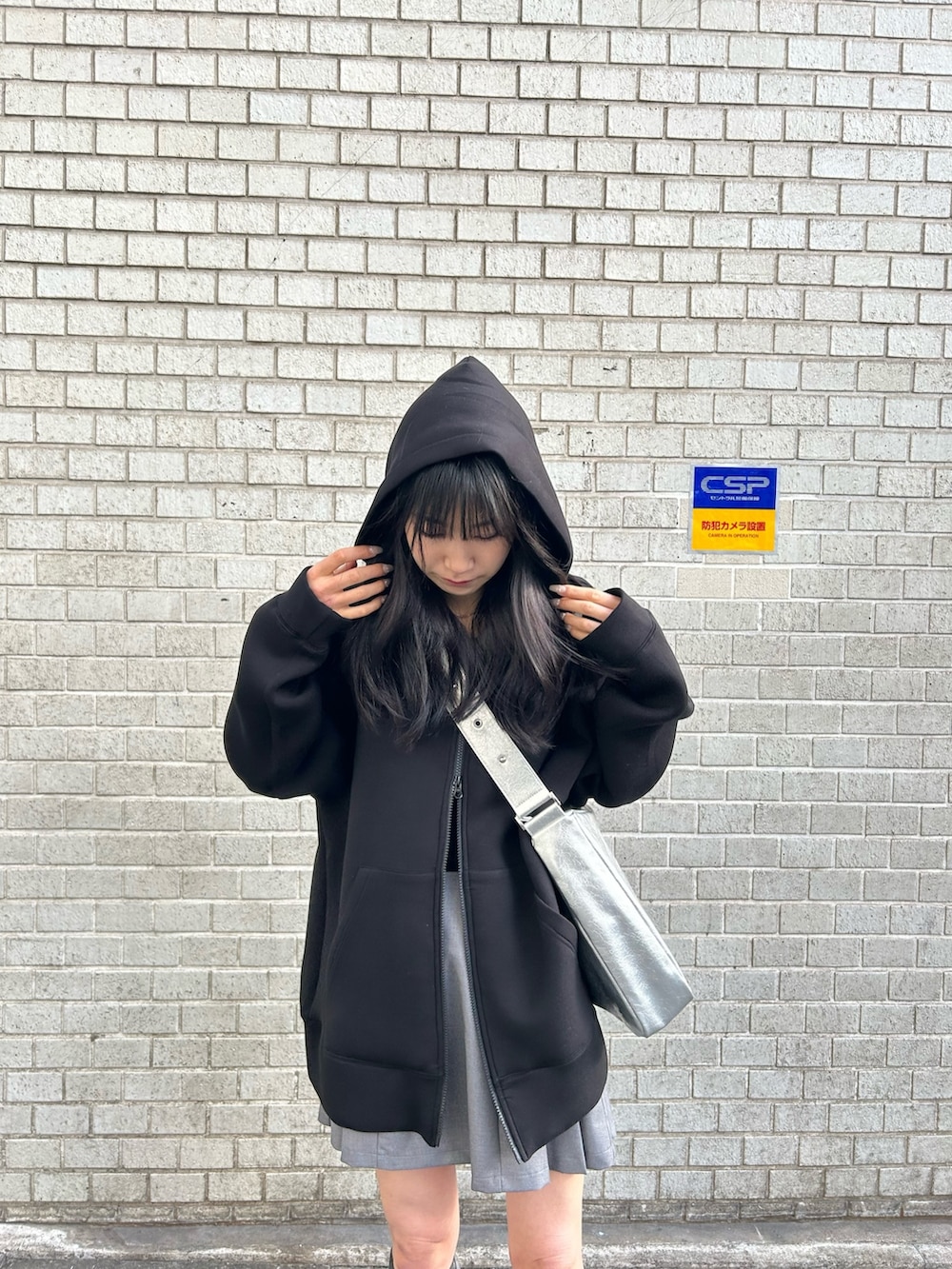 ブラック系のパーカー、グレー系のスカート、シルバー系のショルダーバッグを着用したレディースの冬コーディネートの2枚目の写真