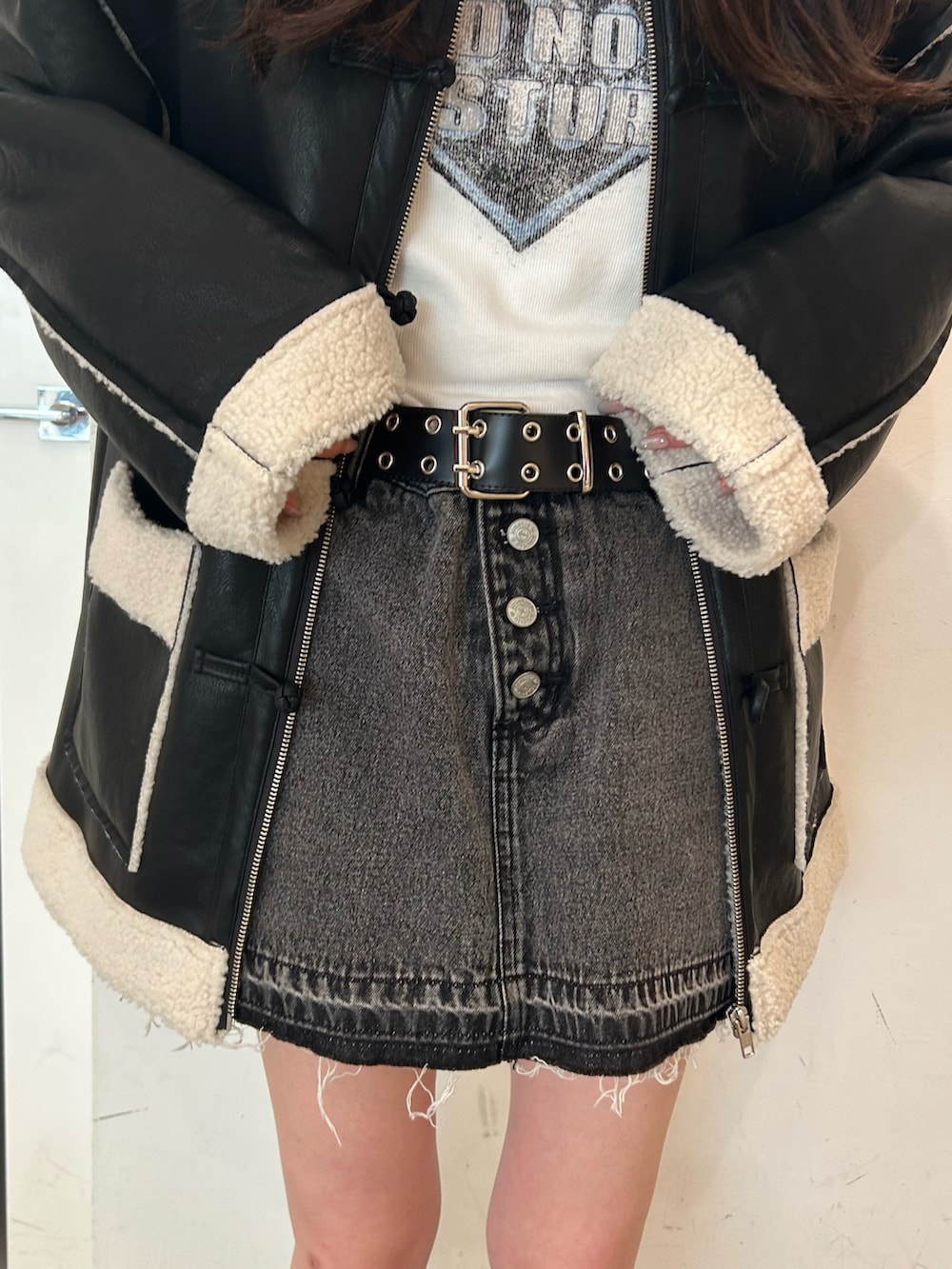 ブラック系のムートンコート、ホワイト系のTシャツ/カットソー、ブラック系のデニムパンツを着用したレディースの夏コーディネートの6枚目の写真