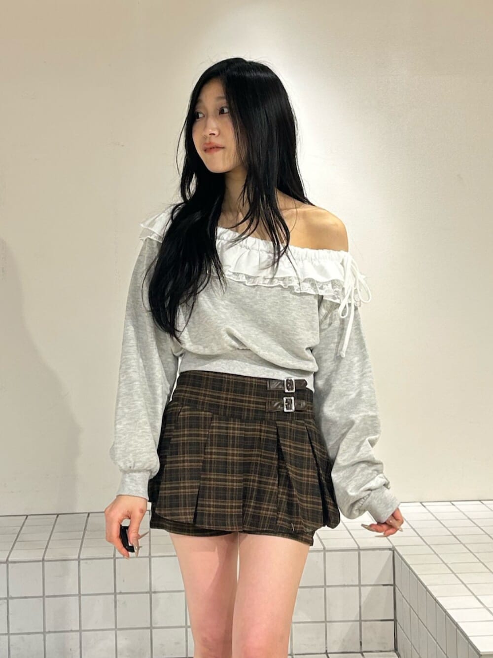 ブラウン系のスカート、グレー系のスウェット、ブラック系のブーツを着用したレディースの冬コーディネートの4枚目の写真