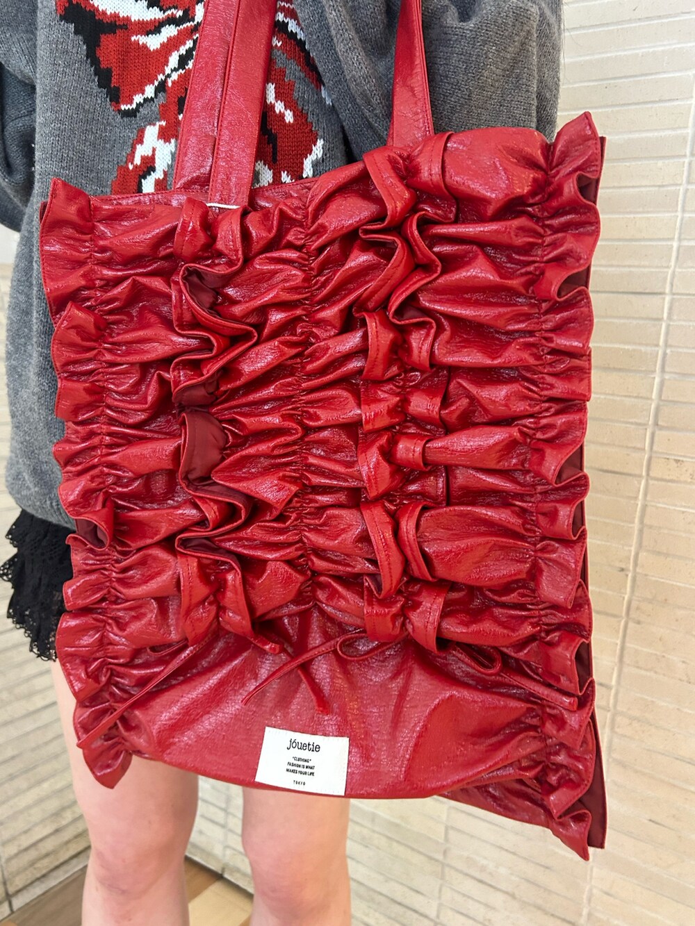 ゴールド系のパンプス、ブラック系のその他パンツ、レッド系のトートバッグを着用したレディースの冬コーディネートの8枚目の写真