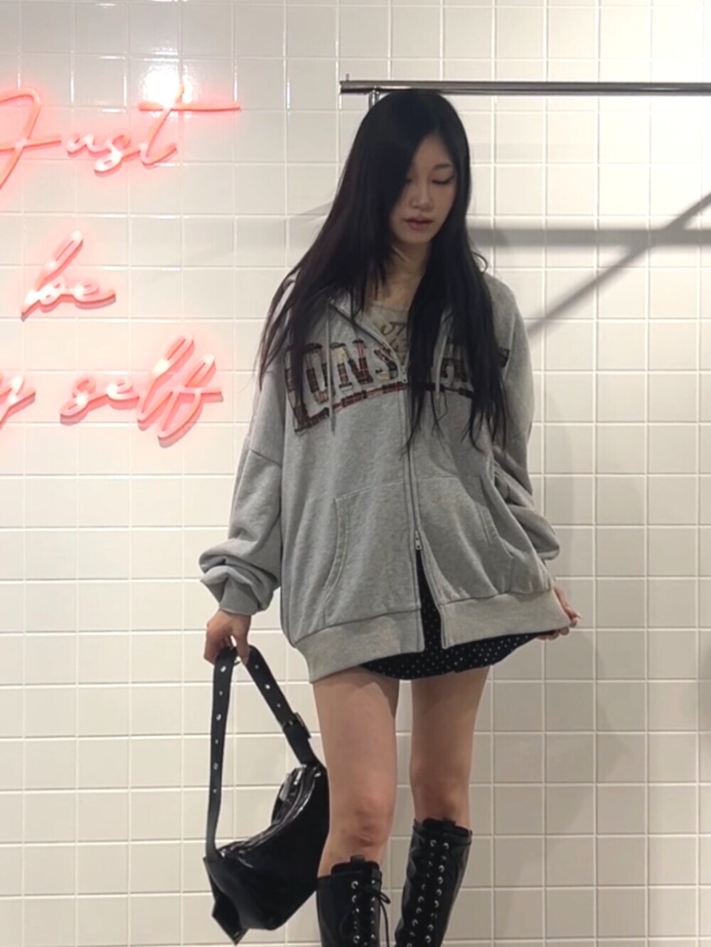 ブラック系のブーツ、グレー系のパーカー、ブラック系のスカートを着用したレディースの秋コーディネートの4枚目の写真