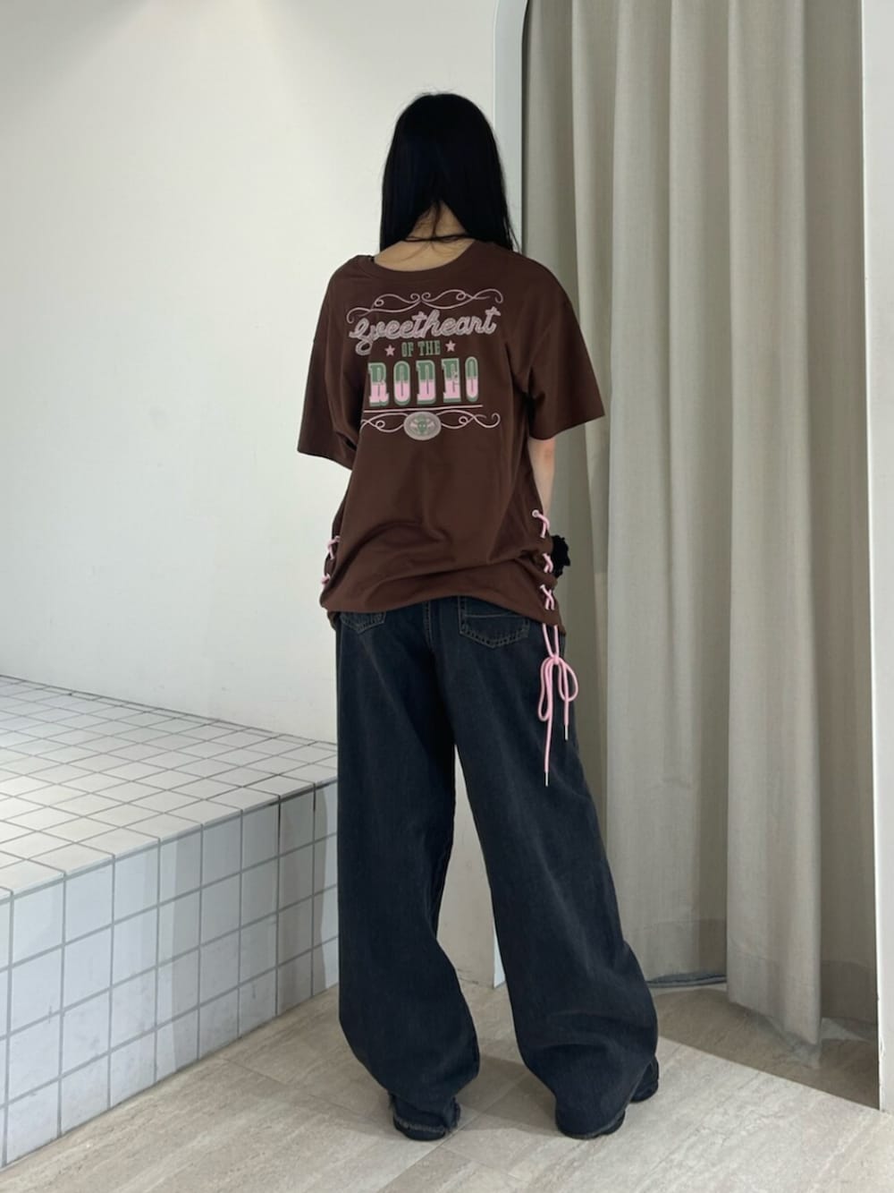 ブラック系のサンダル、ブラック系のデニムパンツ、ブラウン系のワンピースを着用したレディースの夏コーディネートの2枚目の写真