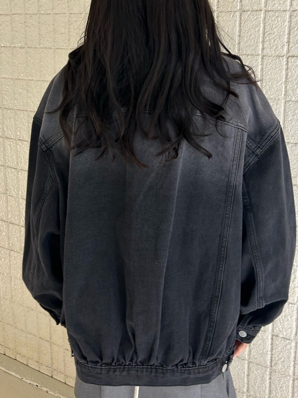 ブラック系のデニムジャケット、ホワイト系のTシャツ/カットソー、グレー系のスカートを着用したレディースの春コーディネートの6枚目の写真