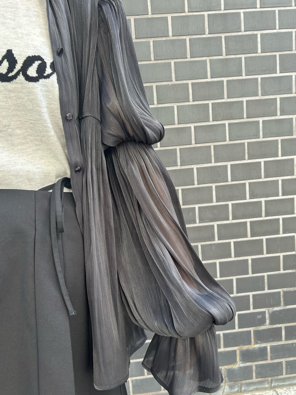 ブラック系のシャツ/ブラウス、ホワイト系のニット/セーター、ブラック系のスカートを着用したレディースの春コーディネートの6枚目の写真