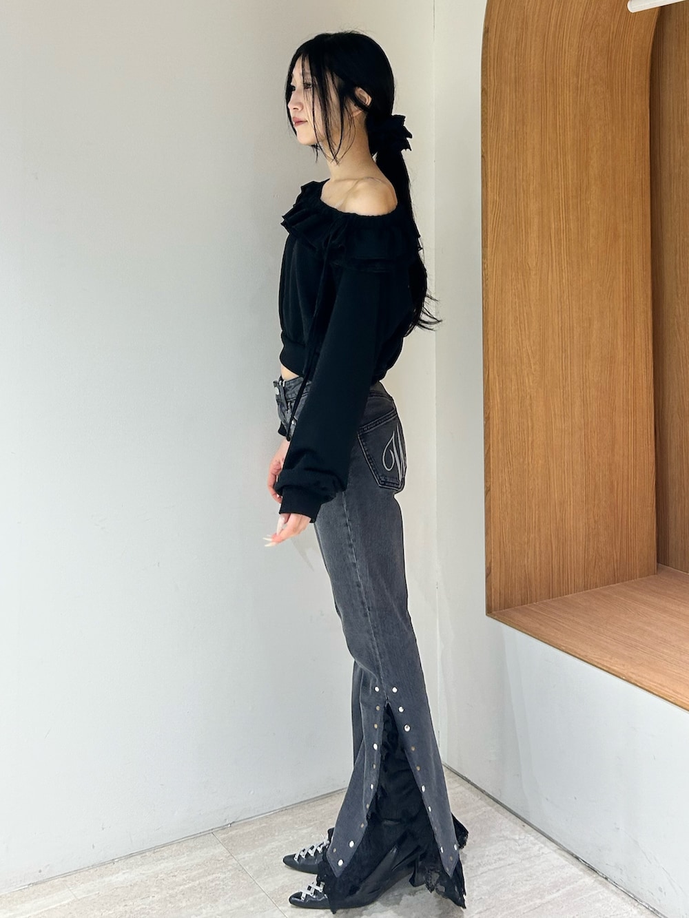 ブラック系のスウェット、ブラック系のデニムパンツ、ブラック系のパンプスを着用したレディースの冬コーディネートの2枚目の写真