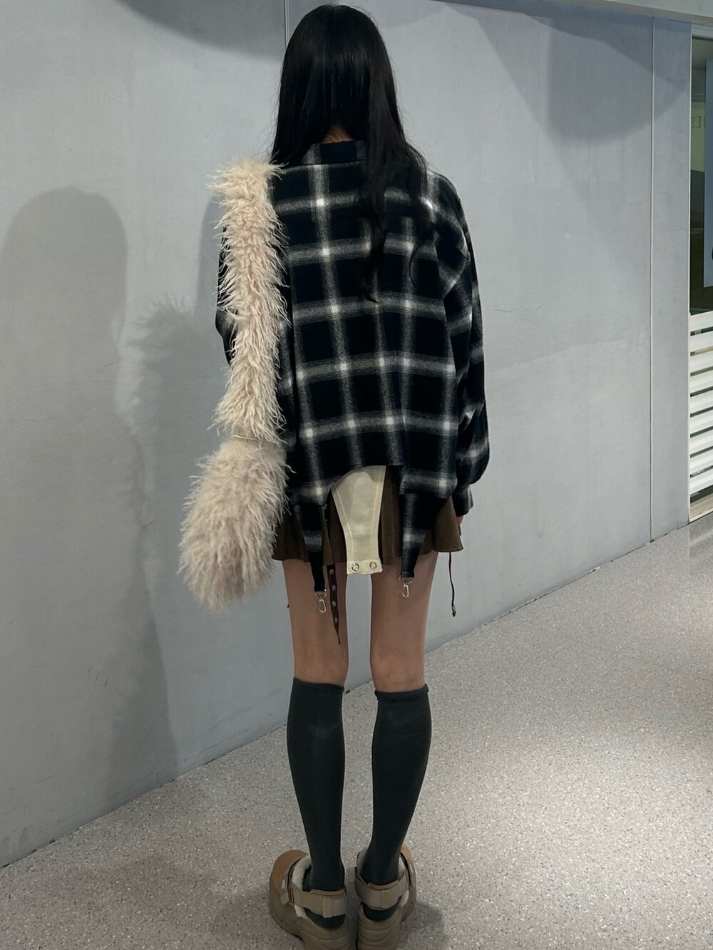 ホワイト系のショルダーバッグ、ベージュ系のブーツ、ブラウン系のスカートを着用したレディースの秋コーディネートの3枚目の写真