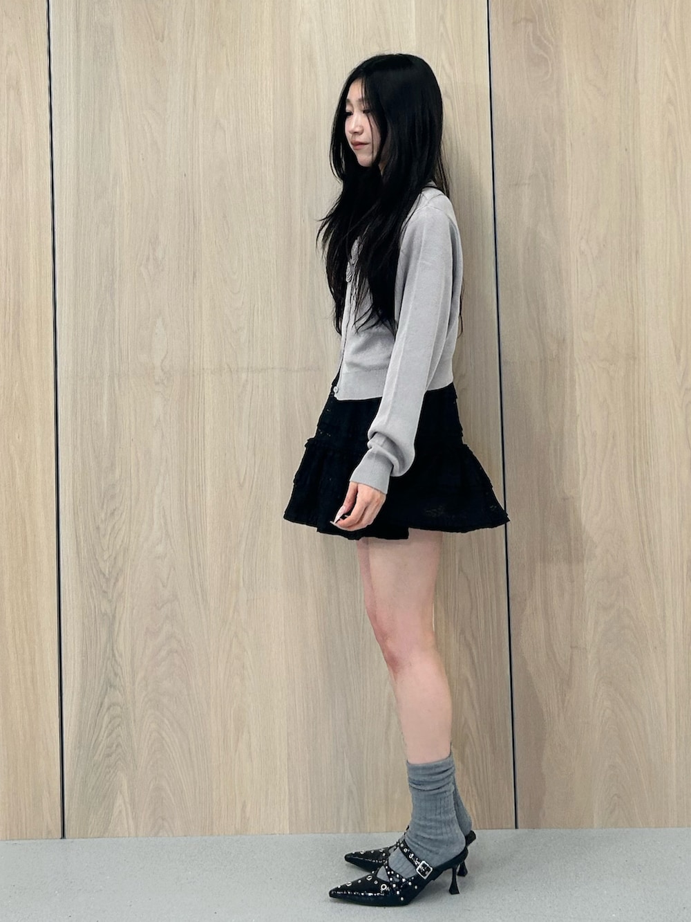 グレー系のニット/セーター、ブラック系のワンピース、ブラック系のパンプスを着用したレディースの春コーディネートの2枚目の写真