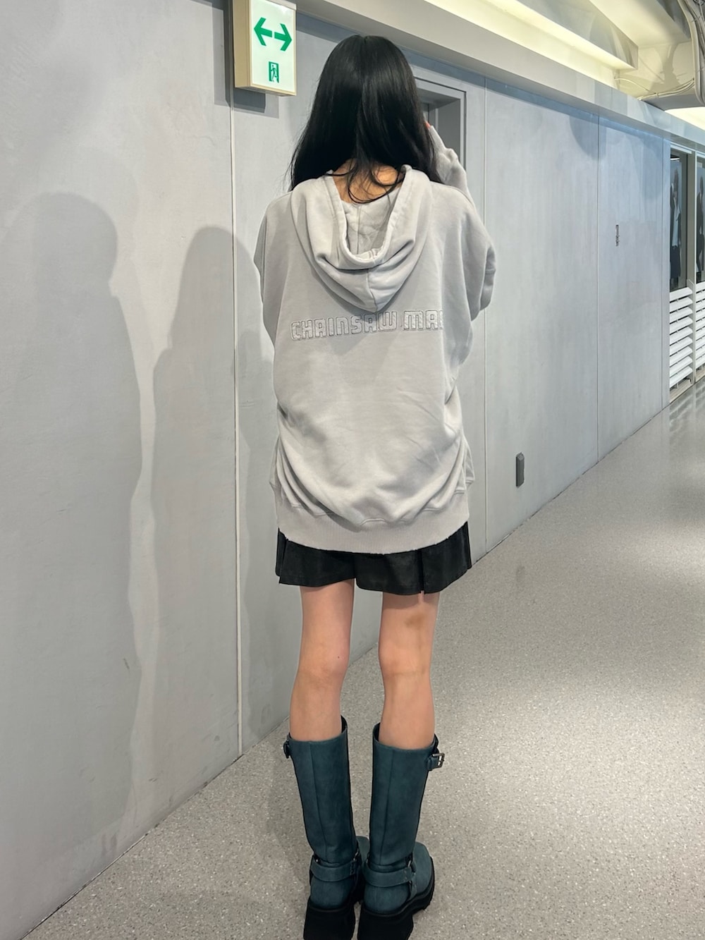 ブルー系のパーカー、ブラック系のスカート、ブルー系のブーツを着用したレディースの秋コーディネートの3枚目の写真