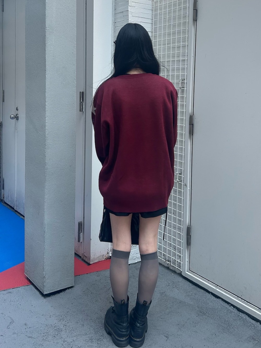 レッド系のニット/セーター、ブラック系のスカート、ブラック系のチョーカーを着用したレディースの秋コーディネートの3枚目の写真