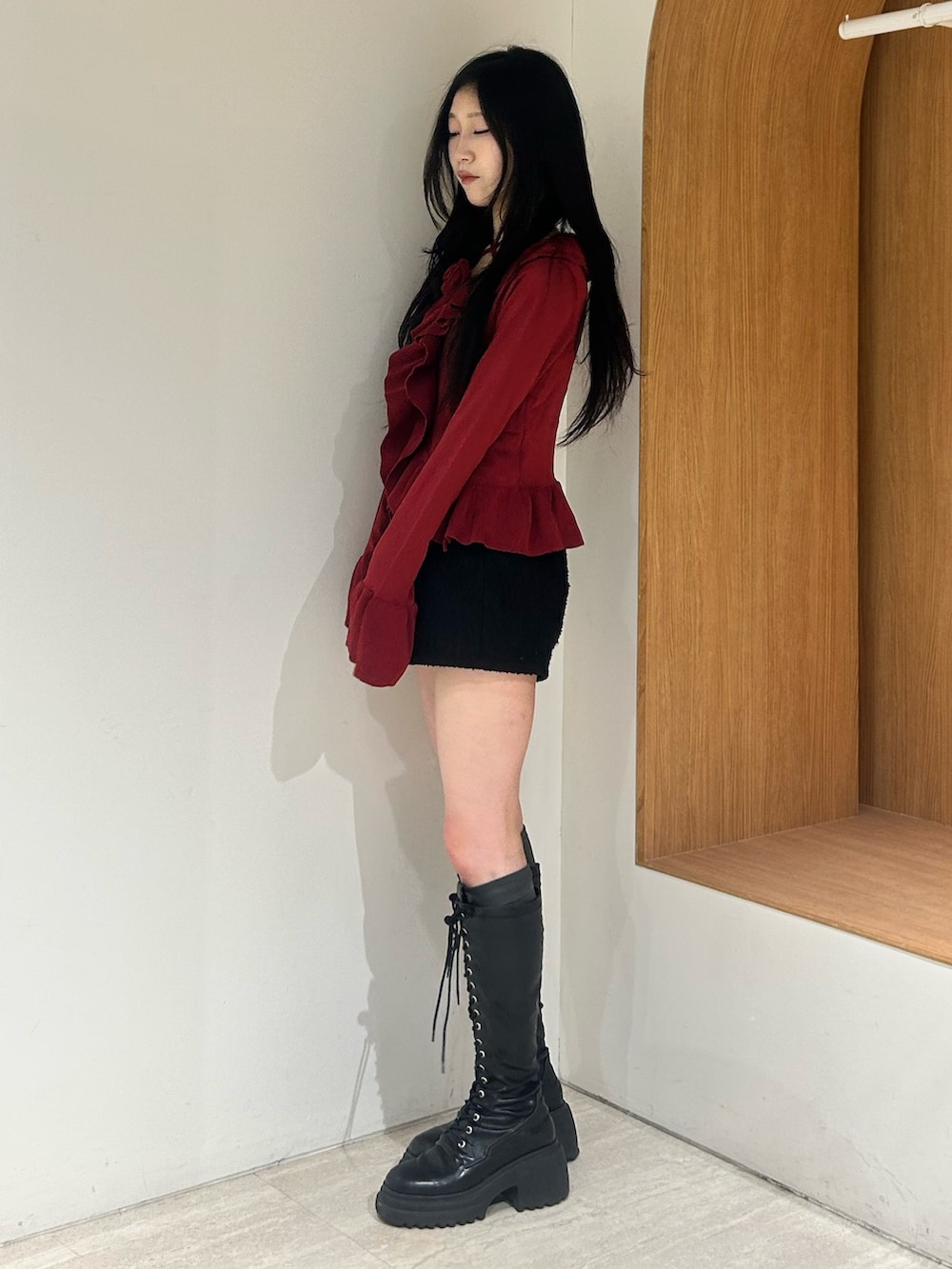 レッド系のニット/セーター、ブラック系のその他パンツ、ブラック系のブーツを着用したレディースの春コーディネートの2枚目の写真