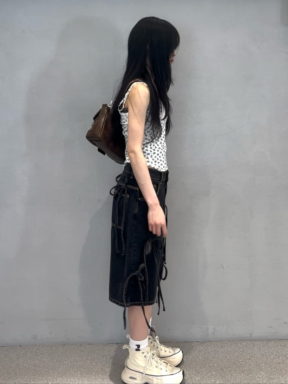 ブラック系のデニムパンツ、ホワイト系のアンサンブル、ホワイト系のスニーカーを着用したレディースの春コーディネートの2枚目の写真